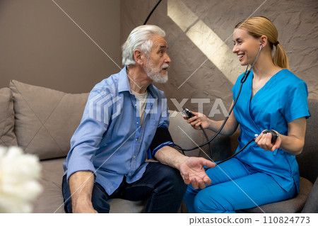 Nurse examining mature patient measuring blood pressure. 110824773