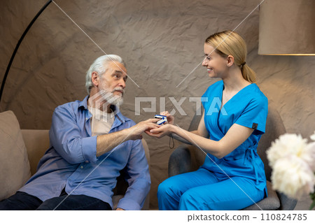 Nurse checking pulse or level of oxygen using oximeter of senior man. 110824785