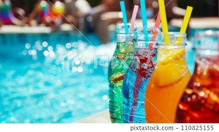 Bottles with your favorite multi-colored natural soft drinks against the backdrop of the pool, concept for advertising refreshing lemonades and juices at a student party in the pool Bottles with your favorite multi-colored natural soft drinks against the backdrop of the pool, concept for advertising refreshing lemonades and juices at a student party in the pool 110825155
