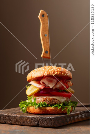 Fresh tasty burger on a wooden cutting board. Fresh tasty burger on a wooden cutting board. 110825189
