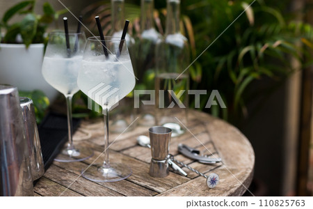 White cocktail with ice in a glass with a stem on a wooden surface 110825763