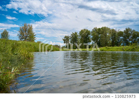 A clean, calm river in the forest on a beautiful sunny summer day. 110825973