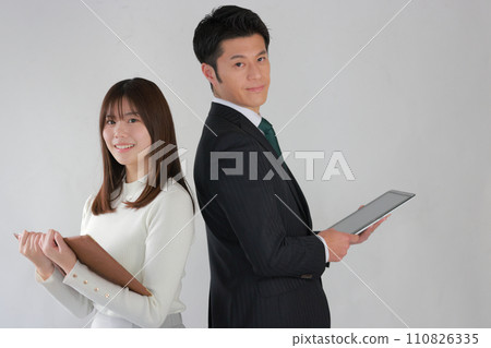 Back to back_Business woman opening a book and businessman holding a tablet_1 110826335