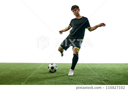Young man, football player in motion during game, hitting ball isolated over white background with grass flooring 110827102