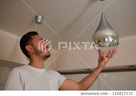 Extreme close-up of unrecognizable man cleaning electric lamp with wet microfiber rag. Close-up of male hands wiping chandelier removing dust at home. Concept of cleaning and household, slow motion. Extreme close-up of unrecognizable man cleaning electric lamp with wet microfiber rag. Close-up of male hands wiping chandelier removing dust at home. Concept of cleaning and household, slow motion. 110827132
