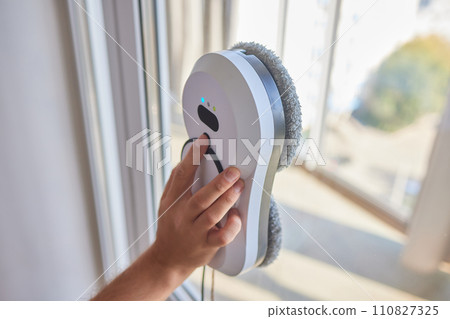 A window cleaner robot washes glass against the backdrop of multi-storey buildings. 110827325