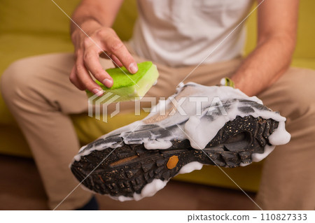 Cleaning suede sneakers. A worker in a shoe workshop cleans a pile of shoes Cleaning suede sneakers. A worker in a shoe workshop cleans a pile of shoes 110827333