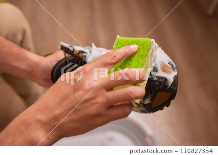 Cleaning suede sneakers. A worker in a shoe workshop cleans a pile of shoes 110827334