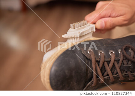 Cleaning suede sneakers. A worker in a shoe workshop cleans a pile of shoes 110827344