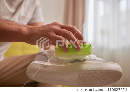 Cleaning suede sneakers. A worker in a shoe workshop cleans a pile of shoes 110827354