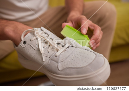 Cleaning suede sneakers. A worker in a shoe workshop cleans a pile of shoes Cleaning suede sneakers. A worker in a shoe workshop cleans a pile of shoes 110827377