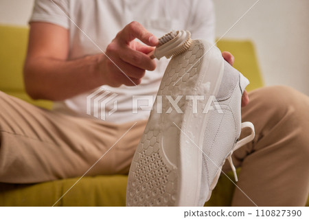 Cleaning suede sneakers. A worker in a shoe workshop cleans a pile of shoes 110827390