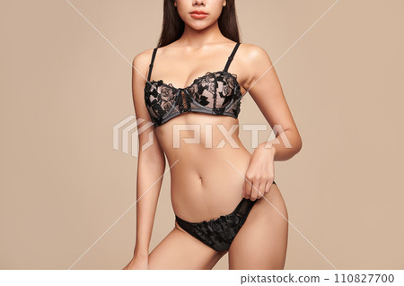 Confident beautiful young asian woman posing in black lingerie on beige background, Perfect body, Confident beautiful young asian woman posing in black lingerie on beige background, Perfect body, 110827700