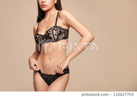 Confident beautiful young asian woman posing in black lingerie on beige background, Perfect body, Confident beautiful young asian woman posing in black lingerie on beige background, Perfect body, 110827703