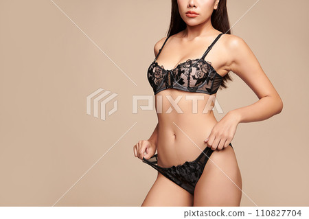 Confident beautiful young asian woman posing in black lingerie on beige background, Perfect body, Confident beautiful young asian woman posing in black lingerie on beige background, Perfect body, 110827704