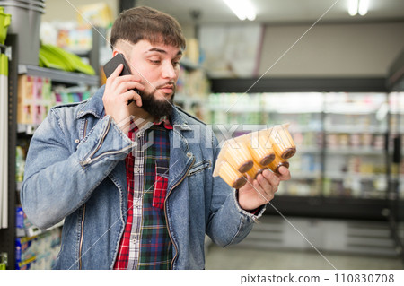 man talking on smartphone about purchasing of yogurts man talking on smartphone about purchasing of yogurts 110830708
