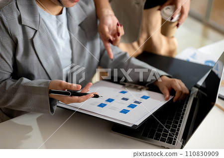 A businesswoman and her boss are working and checking a business report in the office together. A businesswoman and her boss are working and checking a business report in the office together. 110830909