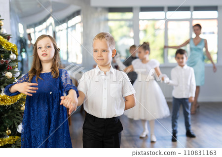 Christmas ball - group of children in festive clothes dances a waltz around New Year tree 110831163