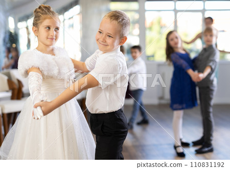 Positive little boys and girls in festive clothes dancing pair dance in ballet studio Positive little boys and girls in festive clothes dancing pair dance in ballet studio 110831192