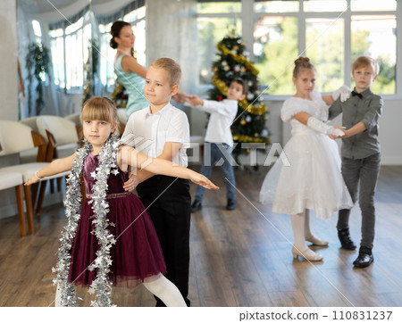 Little children practicing waltz dance in school-hall decorated with Christmas-tree 110831237