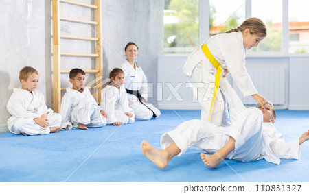 Children in white kimono training judo, jiu-jitsu indoors. Professional sports club for kids. Concept of martial arts, combat sport, sport education, childhood, hobby Children in white kimono training judo, jiu-jitsu indoors. Professional sports club for kids. Concept of martial arts, combat sport, sport education, childhood, hobby 110831327