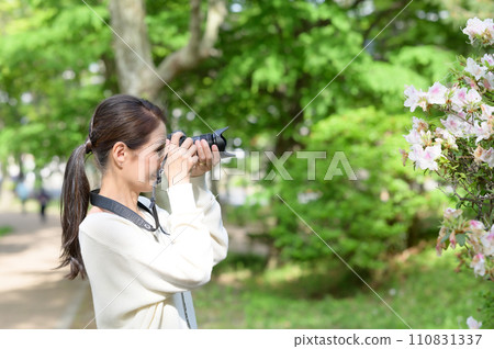 Senior woman taking pictures of flowers with a camera 110831337