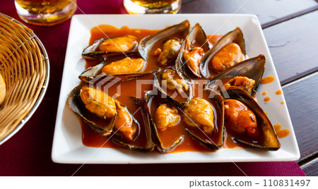 Delicious baked in sauce mussels, served at plate at table 110831497