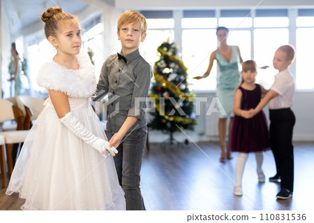 Little children practicing waltz dance in school-hall decorated with Christmas-tree 110831536