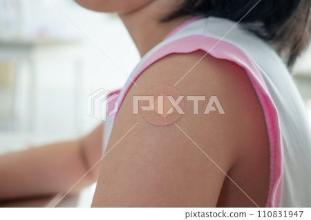 Vaccinated little asian girl with adhesive plaster after vaccine injection 110831947