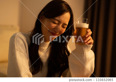 Woman drinking beer in the room at night 110832065