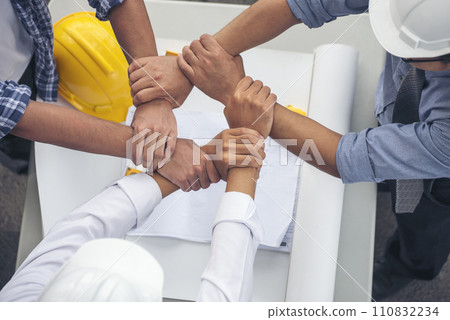 Group of multiracial people Engineer Manager Foreman Teamwork meeting join hands. Close up engineer men hands diversity multiethnic partners team together. Top view office table team join partnership Group of multiracial people Engineer Manager Foreman Teamwork meeting join hands. Close up engineer men hands diversity multiethnic partners team together. Top view office table team join partnership 110832234