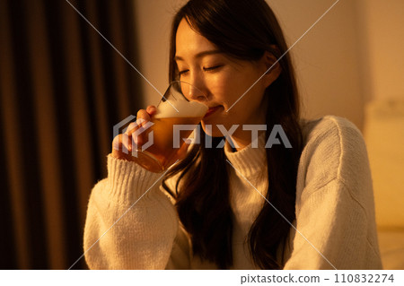 Woman drinking beer in the room at night Woman drinking beer in the room at night 110832274