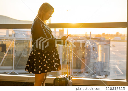 At the airport, under sunlight, a woman is confirming the departure time At the airport, under sunlight, a woman is confirming the departure time 110832815