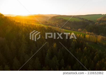 Sunset in the mountains with high trees and valleys.  110832862