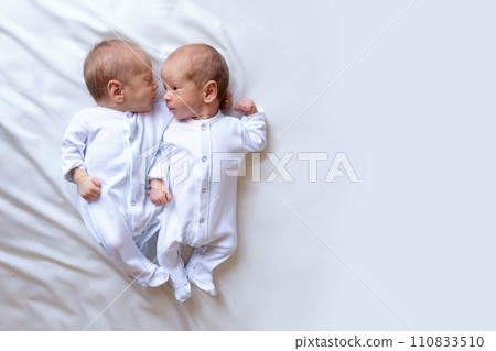 Newborn twins on the bed, in the arms of their parents. Life style, emotions of kids. Newborn twins on the bed, in the arms of their parents. Life style, emotions of kids. 110833510