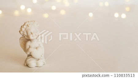 figurine of an angel Cupid with a bow on a pink background. Valentine's Day. 110833513