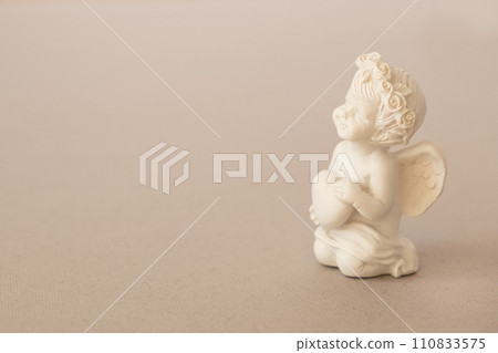 figurine of an angel Cupid with a bow on a pink background. Valentine's Day. 110833575