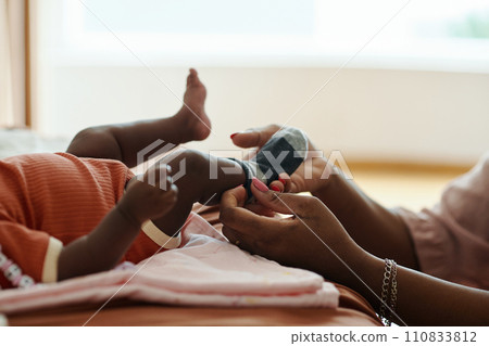 Hands of mother putting small socks on feet of newborn baby 110833812