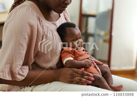 Mother sitting on bed with newborn baby on laps Mother sitting on bed with newborn baby on laps 110833898