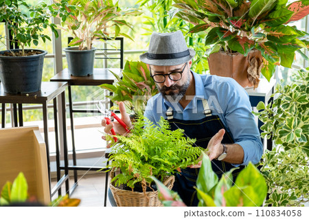 Hipster elderly men take care of the trees, pruning trees with scissors as a hobby of urban home gardening after sustainable retirement 110834058