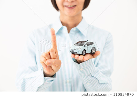 一位中年婦女拿著汽車模型，微笑著舉起食指 110834970