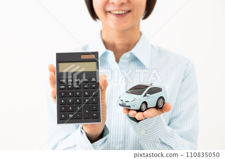 Smiling middle-aged woman with a calculator and a car model Smiling middle-aged woman with a calculator and a car model 110835050