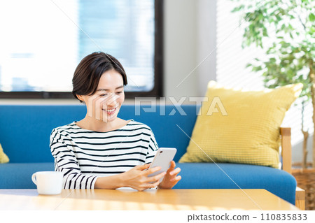 A young woman operating a smartphone. 110835833