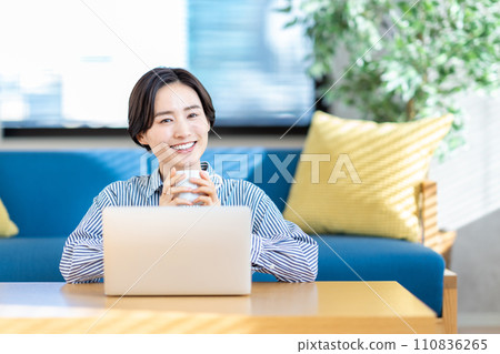 A woman operating a laptop in the living room. 110836265