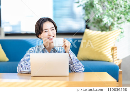 A woman operating a laptop in the living room. 110836268