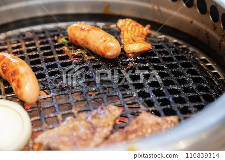 Wiener and beef being grilled on a grill at a yakiniku restaurant 110839314