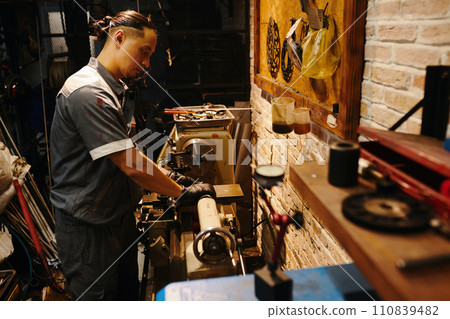 Mechanic using special machine at workbench to fix detail for motorcycle 110839482