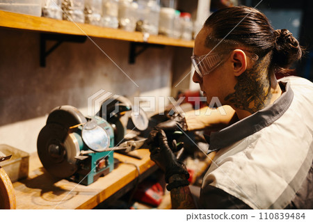 Mechanic in protective googles working at workbench in his garage 110839484