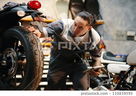 Repairman checking wheels and tires of motorcycle in garage 110839595