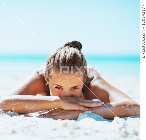 Young woman in swimsuit laying on sandy beach Young woman in swimsuit laying on sandy beach 110842177